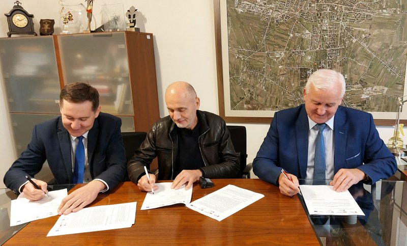 Na zdjęciu trzech mężczyzn podpisuje dokumenty. Podpisanie umowy przez Burmistrza Miasta i Gminy Busko-Zdrój Waldemara Sikorę, skarbnika Artura Tokarza oraz wykonawcy Piotra Kapusty/