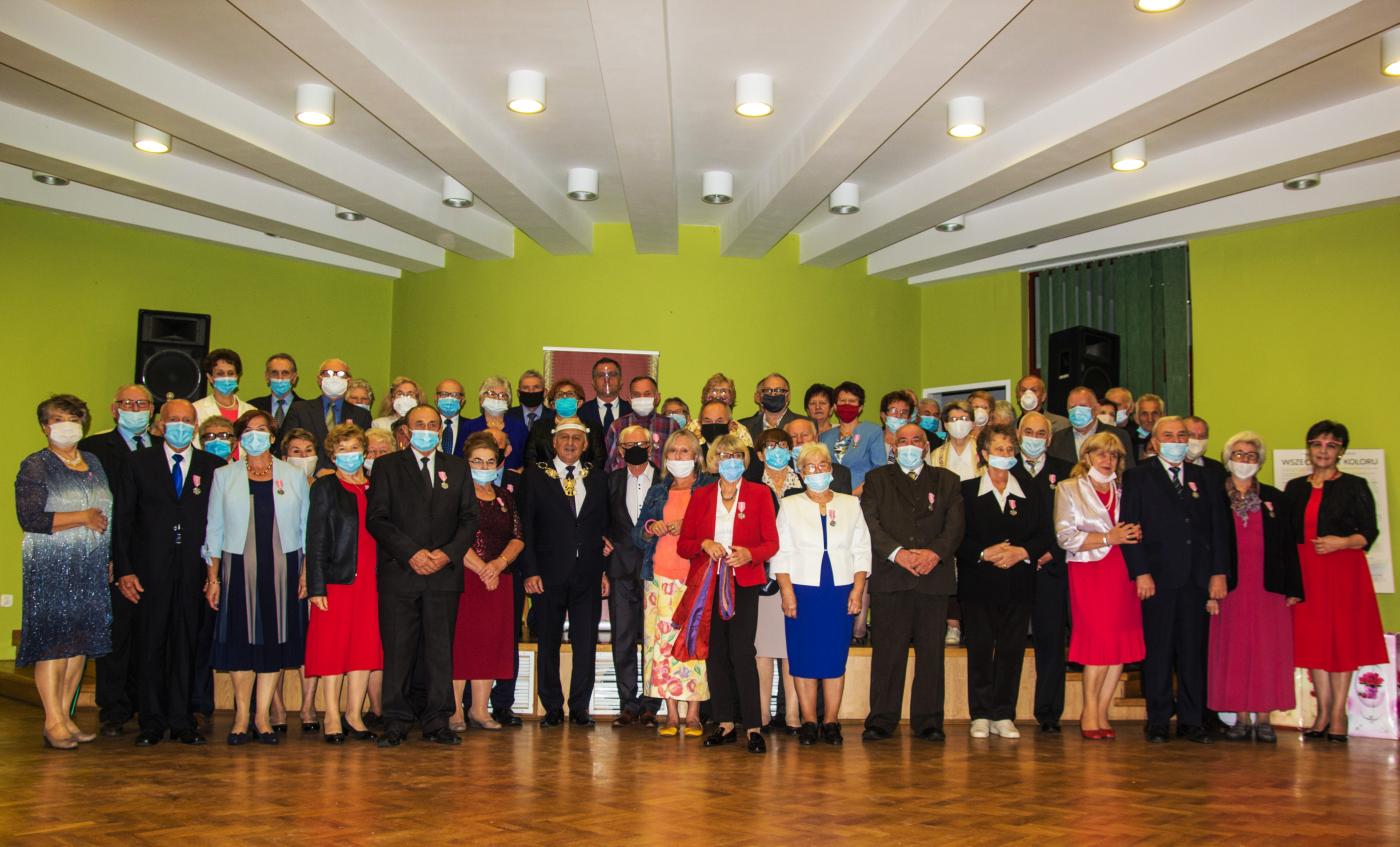 Fotografia przedstawia Burmistrza Miasta i Gminy Busko-Zdrój, Przewodniczącego Rady Miejskiej w Busku-Zdroju oraz Jubilatów podczas uroczystości „Złote gody” zorganizowanej w Buskim Samorządowym Centrum Kultury 