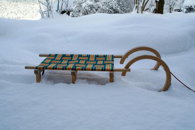Zdjęcie przedstawia kolorowe sanki stojące na śniegu