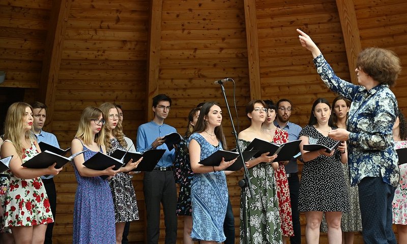 Jeden z chórów na muszli koncertowej. Przed śpiewakami dyrygentka z uniesioną ręką