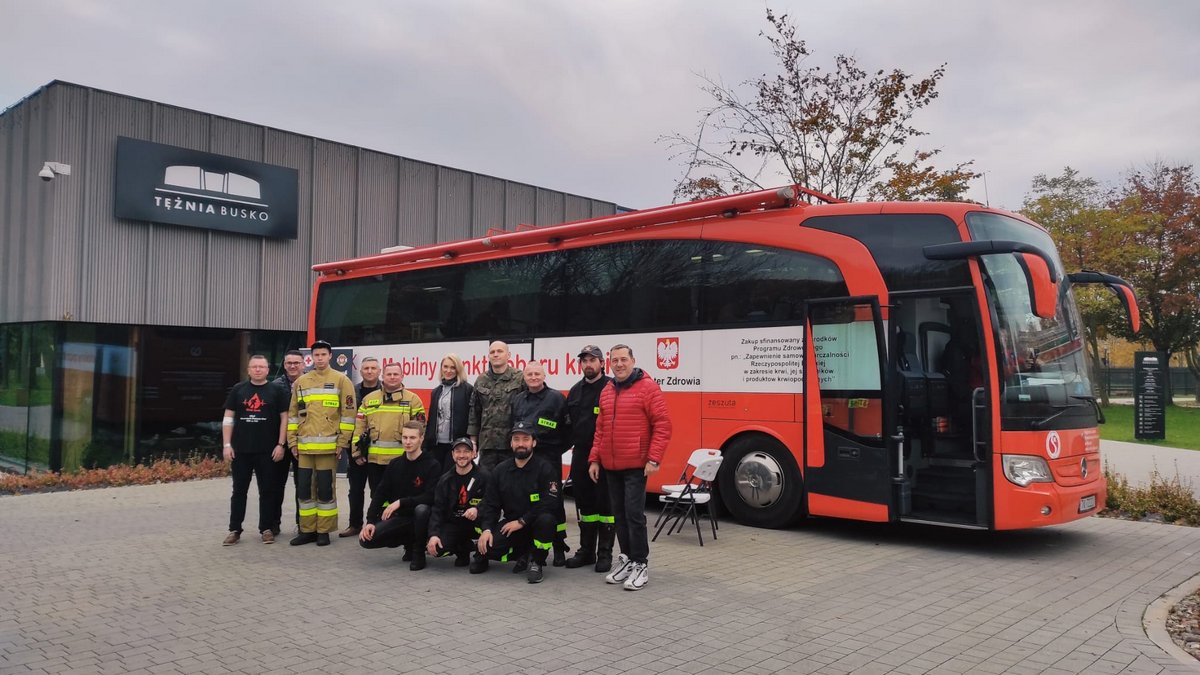 uczestnicy akcji poboru krwi na terenie pozują do zdjęcia na tle domu zdrojowego i autobusu