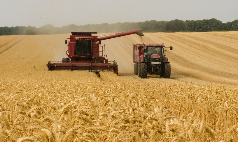 zdjęcie przedstawia kombajn i traktor podczas pracy na polu zboża