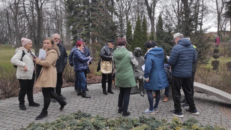 Uczestnicy gry terenowej na temat Wojtka Belona obok rzeźby -ławeczki przedstawiającej artystę