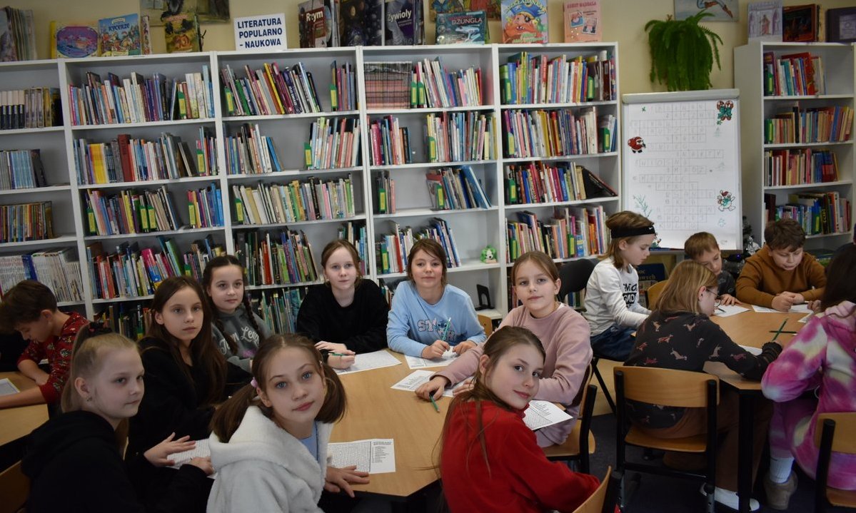 Dzieci podczas zajęc w bibliotece pozują do zdjęcia 