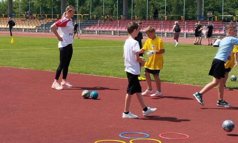 dzieci w strojach sportowych na bieżni stadionu