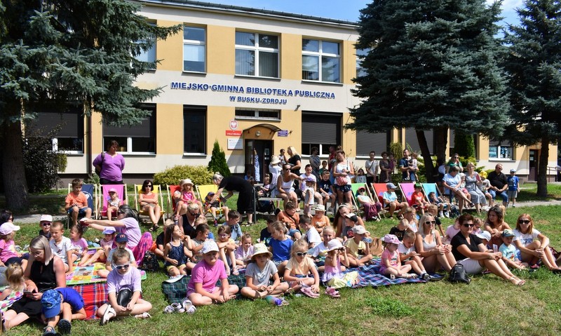 dzieci siedza przed biblioteka