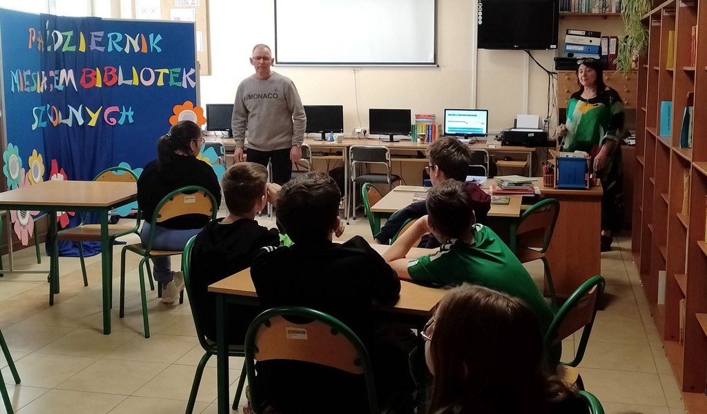 Mężczyzna i kobieta stoją a dzieci siedzą przy stolikach