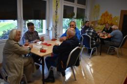 Grupa-osob-siedzi-przy-dwoch-stolikach-i-gra-w-karty