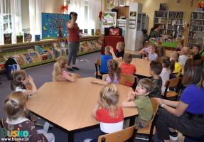 Kobieta prezentuje dzieciom karty biblioteczne