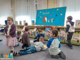 Dzieci podczas zabawy na podłodze, w tle niski regał na książki