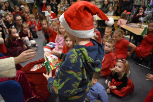 chopiec-w-czapce-Mikoja-trzyma-w-doniach-zielone-pudeko-a-w-tle-wida-inne-dzieci