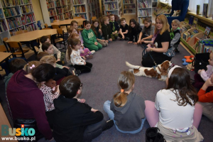 Kobieta z pieskiem oraz dzieci siedzą na dywanie