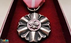 Zdjęcie przedstawia medal na czerwonym tle.