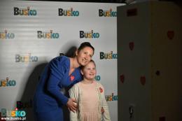 Kobieta z dzieckiem pozuje przed ścianką promocyjną Gminy Uzdrowiskowej Busko-Zdrój