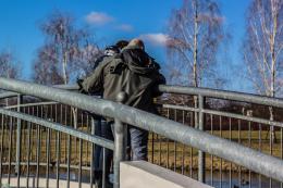 Zdjęcie przedstawia stojacych na mostku obejmującą się parę