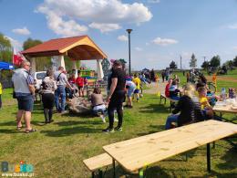 Zdjęcie przedstawia uczestników w trakcie pieczenia kiełbaski