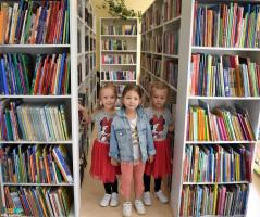 Przedszkolaki Papużki między regałami  bibliotecznymi