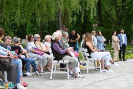 Publiczność siedząca na ławkach przed muszlą koncertową