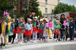 NA zdjęciu dzieci w kwiecistych strojach na placu przed fontanną