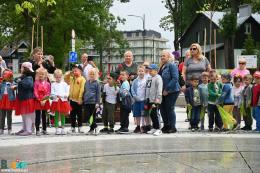 kolorowo ubrane dzieci stojące przy fontannie