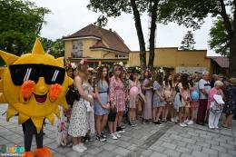 Maskotka - Słoneczko oraz młodzież w kwiecistych strojach uczestnicząca w korowodzie