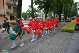NA zdjęciu widać mażoretki w czerwonych i zielonych strojach z pomponami w rękach