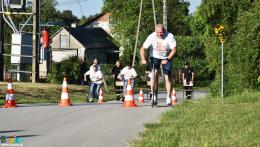 Na pierwszym planie mężczyzna na hulajnodze, w tle kolejni zawodnicy