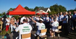 Zawodnicy ubijający masło, kobieta podnosi rękę w geście zwycięstwa