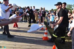 Zawodnicy rzucają kapeluszami w kierunku pachołków, w tle publiczność