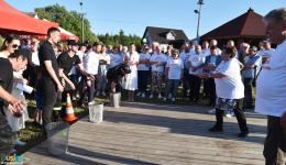 Zawodnicy rzucają piłeczkami do koszy, w tle publiczność