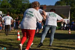Trwa konkurencja powożenia zaprzęgiem. Dwie biegnące kobiety z zawiązanymi oczami, za nimi kolejna odgrywająca rolę woźnicy 