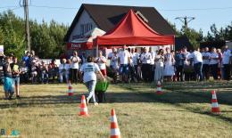 Zawodnik biegnący z załadowanymi taczkami, w tle publiczność