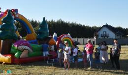 Na zdjęciu osoby oczekujące w kolejce na dmuchaną zjeżdżalnię  dla dzieci