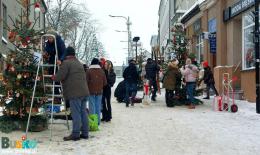 osoby dekorujące świąteczne choinki na placu Zwycięstwa
