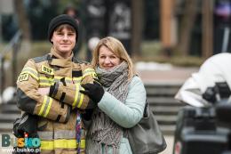Osoby pozujące do zdjęcia - kobieta i młody mężczyzna w stroju strażackim