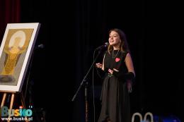 Trwa część artystyczna - na scenie kobieta przed  mikrofonem