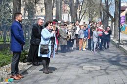 Przemawia pani Maria Nogaś, organizatorka wydarzenia, w tle uczestnicy Marszu Katyńskiego na al. Mickiewicza