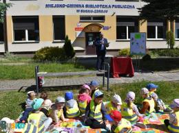 Dzieci siedzą na trawniku przed budynkiem